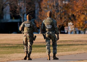 Two National Guard soldiers walk around the Washington Monument in Washington, DC on Dec. 1, 2025.