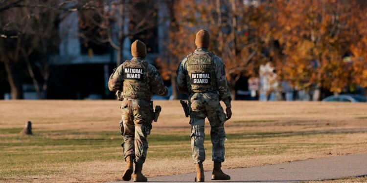 Two National Guard soldiers walk around the Washington Monument in Washington, DC on Dec. 1, 2025.