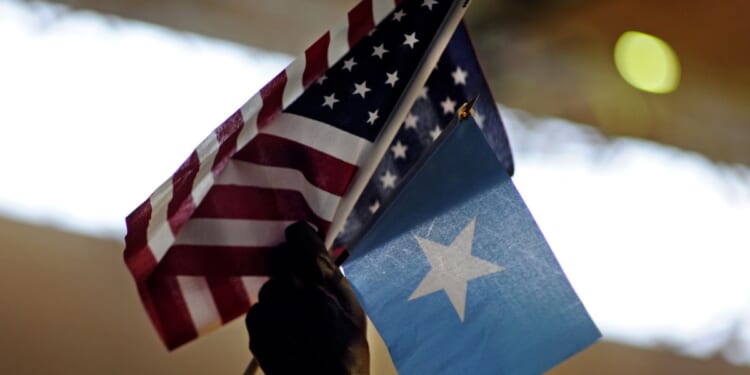 Saeed Fahra holds high U.S. and Somali flags as he speaks to a mostly young male audience during a break in the action of Somali Week's Hoops for Hope basketball tournament at the Richard Green Central Park Community School gym on June 26, 2011, in Minneapolis, Minnesota.