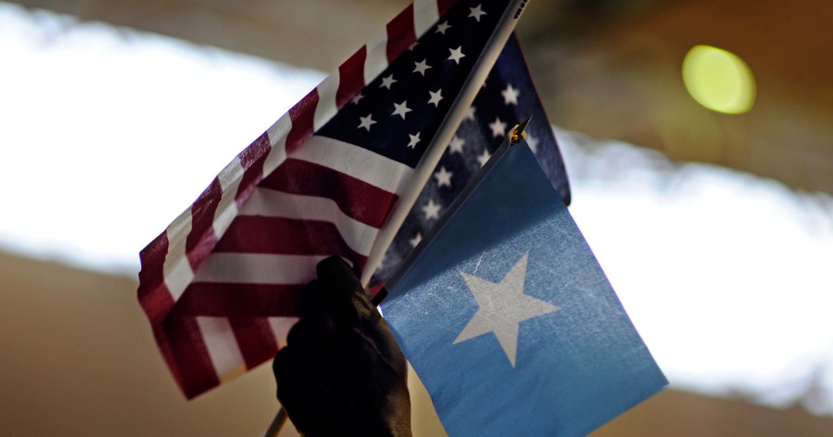 Saeed Fahra holds high U.S. and Somali flags as he speaks to a mostly young male audience during a break in the action of Somali Week's Hoops for Hope basketball tournament at the Richard Green Central Park Community School gym on June 26, 2011, in Minneapolis, Minnesota.