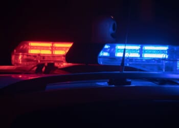 Police lights flash at night in a city.