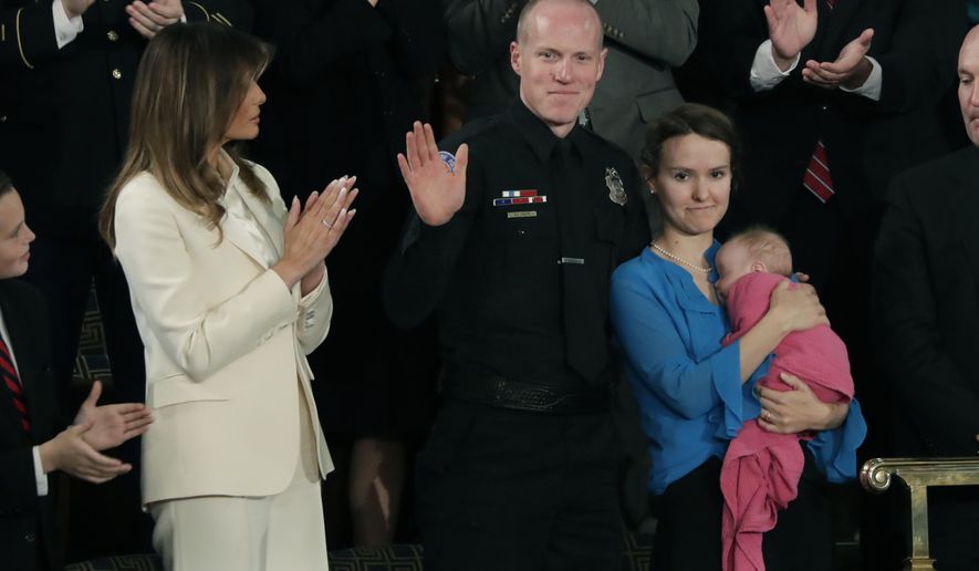 FILE - In this Jan. 30, 2018, file photo, Albuquerque Police Officer Ryan Holets and his wife Rebecca acknowledge their introduction by President Donald Trump as they stand with first lady Melania Trump during the State of the Union address on Capitol Hill in Washington. The face, uniform, and badge of officer Holets, respected for protecting local residents is being used as part of an anti-abortion billboard without his permission, his superiors say. The Albuquerque Police Officer appears on a billboard along an interstate that runs through the city, along with the words "My favorite right is life." (AP Photo/J. Scott Applewhite, File)