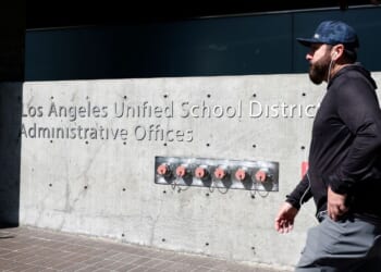 A person walks by a sign in front of the Los Angeles Unified School District headquarters Wednesday in Los Angeles, California. The FBI served search warrants at the Los Angeles Unified School District's headquarters and the home of Superintendent Alberto Carvalho as federal officials work on an ongoing investigation.
