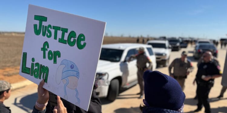 A protestor holds an anti-ICE signs during a demonstration and vigil outside the South Texas Family Residential Center in Dilley, Texas, on Jan. 28, 2026.