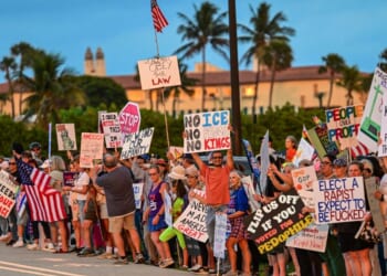 Protesters hold signs near President Donald Trump's Mar-a-Lago resort during the "No Kings" national day of protest, in Palm Beach, Florida, on May 28, 2026.