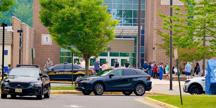 Parents, faculty, and students gather outside the main entrance of Fairfax High School after a 911 call was received from the school in Fairfax, Virginia, on June 6, 2023.