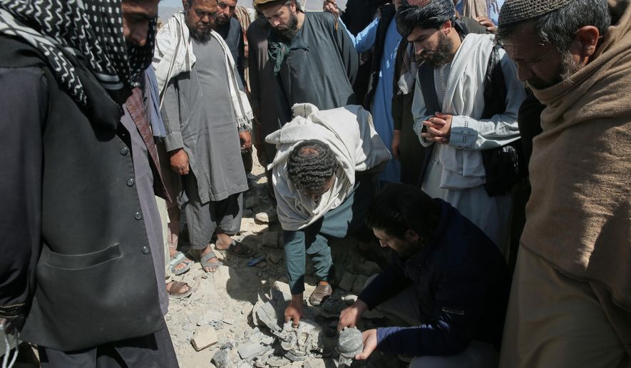 Residents and Taliban police gather the remains of a projectile at the site of a strike in Kabul, Afghanistan, Friday, March 13, 2026. (AP Photo/Barackatullah Popal)