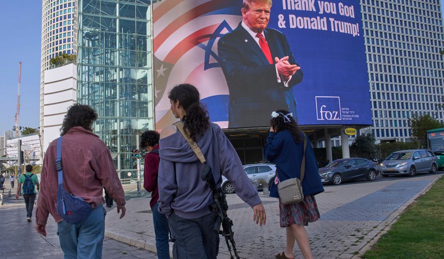 People pass by an electronic billboard displaying an image of President Donald Trump alongside the message "Thank you God and Donald Trump" referring to the U.S. involvement in the war between Israel and Iran, in Tel Aviv, Israel, Thursday, March 12, 2026. (AP Photo/Ohad Zwigenberg)