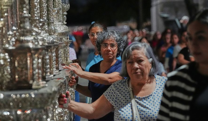 Members of the Corpus Christi Catholic Church push a large float that will carry the Lady of Hope Macarena during a rehearsal of their Good Friday procession Monday, March 23, 2026, in Miami, Fla. (AP Photo/Marta Lavandier)