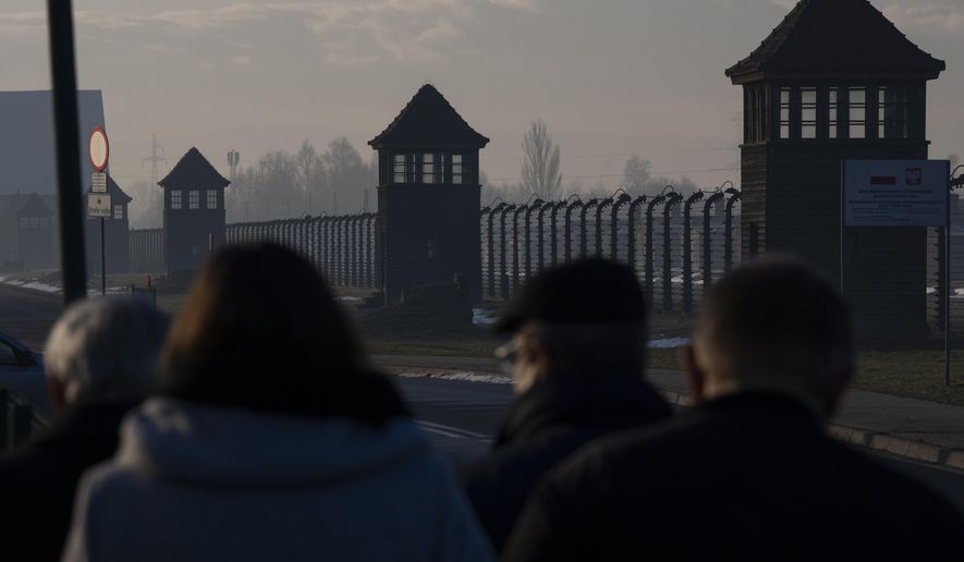 People walk outside the former Nazi German concentration and extermination camp Auschwitz-Birkenau in Oswiecim, Poland, a day before the 80th anniversary of its liberation, Sunday, Jan. 26, 2025. (AP Photo/Oded Balilty)