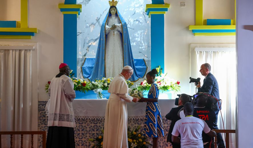 Pope Leo XIV receives flowers he put under the statue of the Virgin Mary in the Church of Our lady of Muxima, on the seventh day of an 11-day apostolic journey to Africa, in Muxima, Angola, Sunday, April 19, 2026. (Guglielmo Mangiapane/Pool Photo via AP)