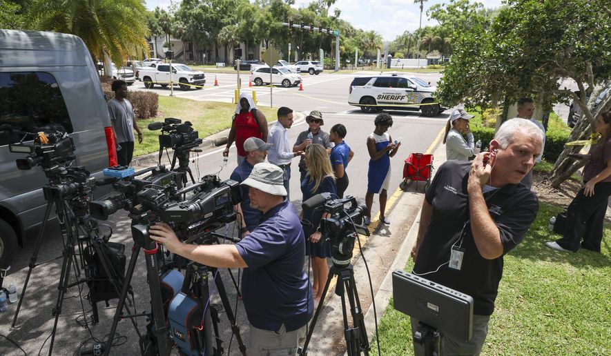 Members of the media document detectives and deputies with the Hillsborough County Sheriff's Office as they investigate inside the Lake Forest subdivision of Tampa, Fla., on Friday, April 24, 2026, where authorities said a man was taken into custody after barricading himself inside a home, in connection to the search for two missing University of South Florida graduate students. (Douglas R. Clifford/Tampa Bay Times via AP)