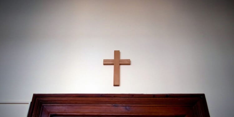 A wooden cross hangs over a door in an empty classroom at the Domgymnasium grammar school in Magdeburg, eastern Germany, on March 25, 2020.
