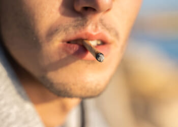 Extreme close-up of a male smoking a joint.