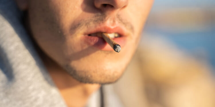 Extreme close-up of a male smoking a joint.