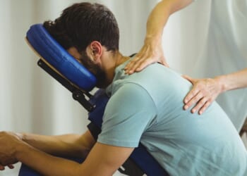 A therapist gives a back massage to a patient in a clinic.