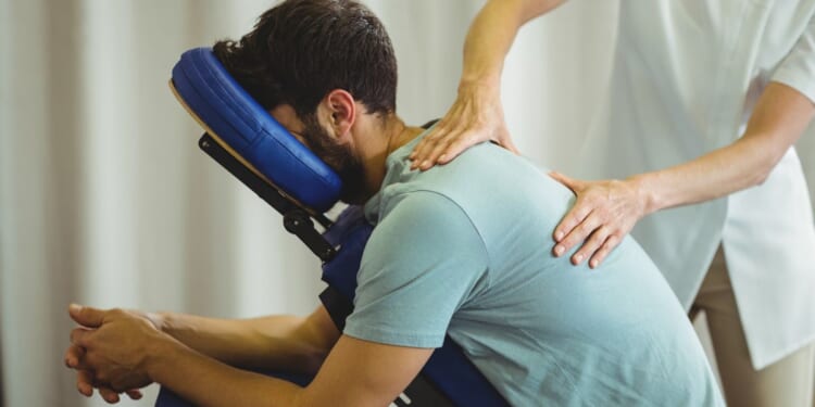 A therapist gives a back massage to a patient in a clinic.