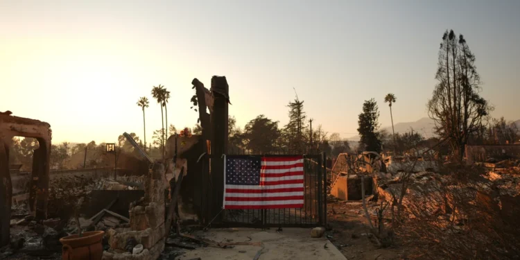 An American flag hangs on the fence of a scorched home in Altadena, California on January 10, 2025