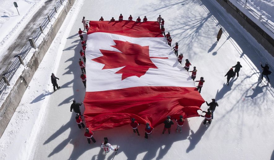 Local youth skate with a large Canadian flag on the Rideau Canal to launch celebrations for the 60th Anniversary of the National Flag of Canada Day, Friday, Feb. 14, 2025, in Ottawa. (Adrian Wyld/The Canadian Press via AP) ** FILE **
