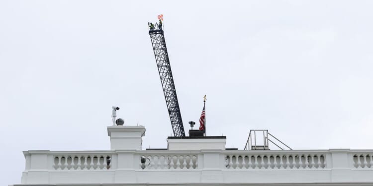 Workers are seen on top of a construction crane above the White House on April 28, 2026, in Washington, D.C.