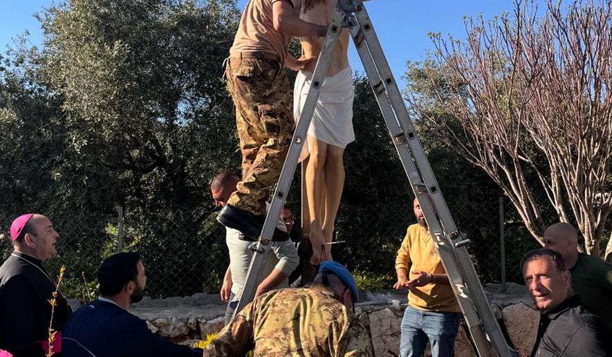 An Italian peacekeeper sets up a crucifix that was sent by Italy to replace one that was defaced last week by an Israeli soldier in the Christian village of Debel, south Lebanon, Wednesday, April 22, 2026. (Hossam Naddaf via AP)