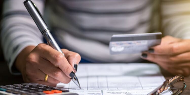 Woman looks at card and writes on a form.