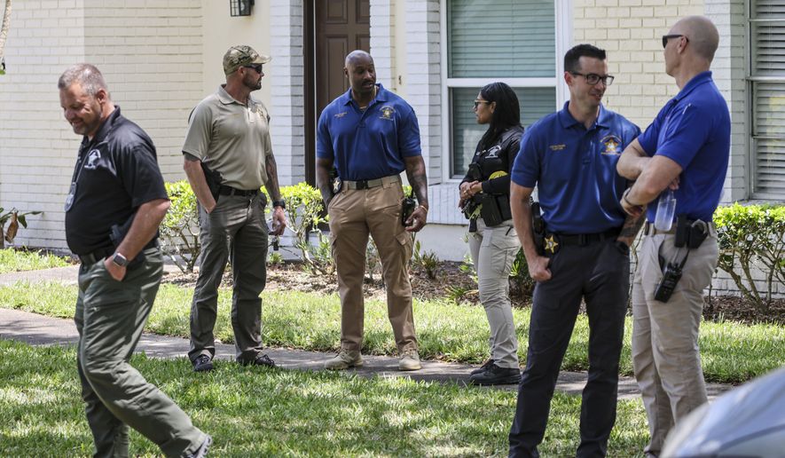 Detectives with the Hillsborough County Sheriff's Office join an investigation inside the Lake Forest subdivision of Tampa, Fla., on Friday, April 24, 2026, where authorities said a man was taken into custody after barricading himself inside a home, in connection to the search for two missing University of South Florida graduate students. (Douglas R. Clifford/Tampa Bay Times via AP)