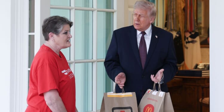 President Donald Trump receives a DoorDash delivery of McDonald's from Sharon Simmons before he speaks to the press during an event outside the Oval Office of the White House on April 13, 2026, in Washington, D.C.