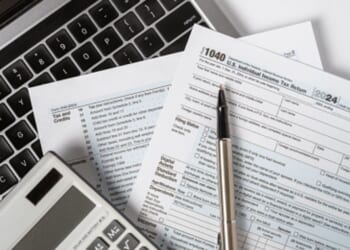 Papers and calculating tools are thrown across a desk.