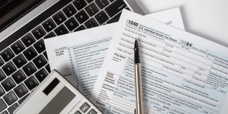 Papers and calculating tools are thrown across a desk.
