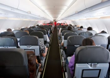 The inside of the cabin of a commercial airline flight with several passengers onboard.