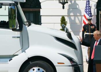 President Donald Trump reaches out to pat the hood of a truck at an event to celebrate America's Truckers at the White House in Washington, DC on April 16, 2020.