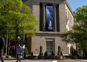 The Department of Justice stands with a poster of Donald Trump hanging from the pillars on April 7, 2026.