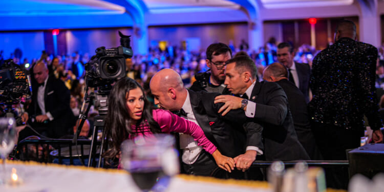 White House Deputy Chief of Staff Steven Miller protects his wife as agents try to usher him out of White House Correspondents' Dinner.