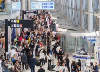 Passengers walk through a busy airport