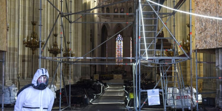 A clearance worker wearing a protective suit stands at the entrance of Nantes Cathedral, severely damaged by a fire in July, in Nantes, western France, on Feb. 26, 2021.