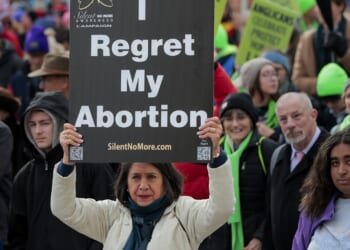 Pro-life protestors holding a sign that says "I regret my abortion."