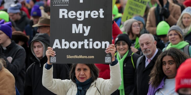 Pro-life protestors holding a sign that says "I regret my abortion."