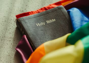 The Holy Bible wrapped in a rainbow-colored flag.