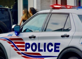 A Metropolitan Police cruiser responds to a call in historic Georgetown as two women walk by in the background, in Washington, D.C., on Aug. 16, 2024.