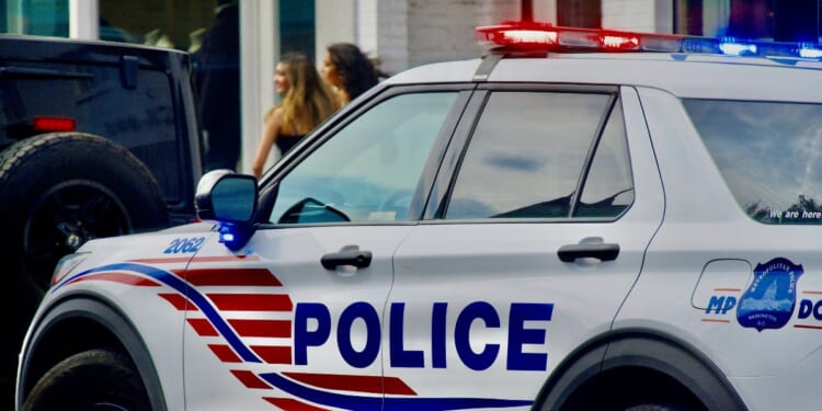 A Metropolitan Police cruiser responds to a call in historic Georgetown as two women walk by in the background, in Washington, D.C., on Aug. 16, 2024.