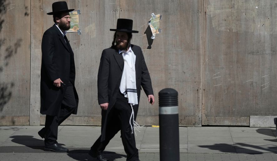 Two men walk in London, Thursday, April 30, 2026, near the scene where two people were recently stabbed in the Golders Green neighbourhood, that has a large Jewish community. (AP Photo/Alastair Grant)