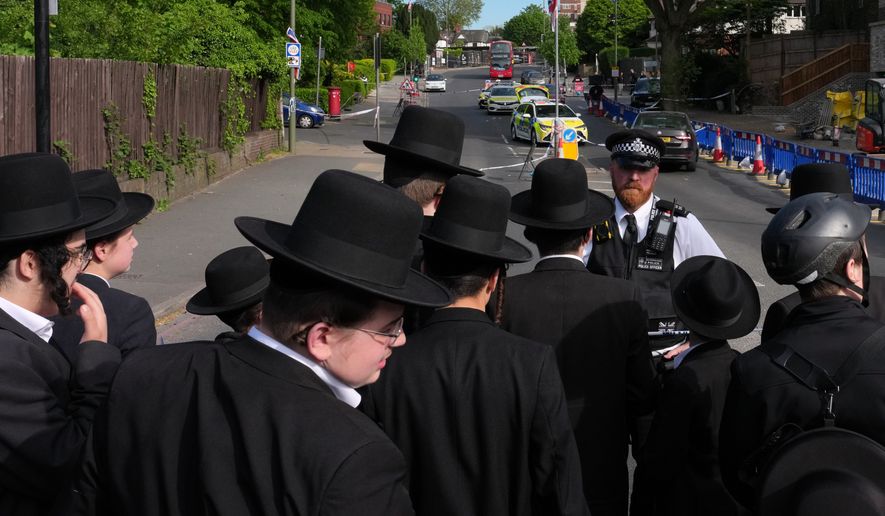 FILE - Members of the community watch as forensic officers search the area after two people were stabbed in the Golders Green neighborhood, that has a large Jewish community, in London, April 29, 2026. (AP Photo/Kin Cheung, File)