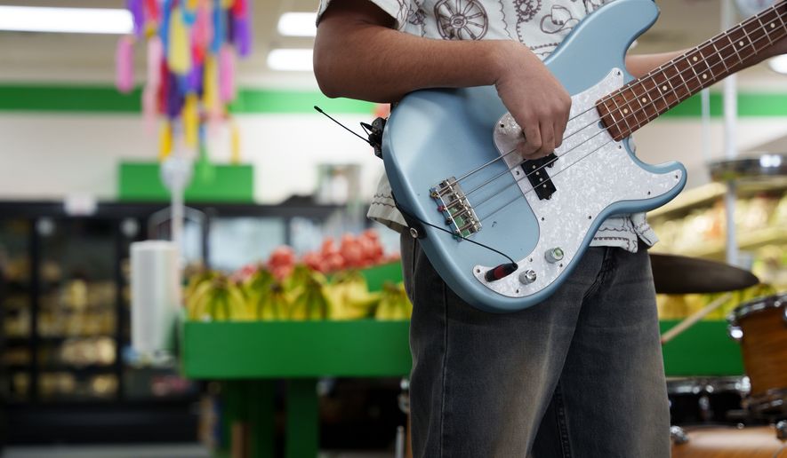 A guitarist performs in the produce section of Fiesta Fresh Market in New Castle, Del., on Sunday, April 26, 2026. (AP Photo/Mingson Lau)