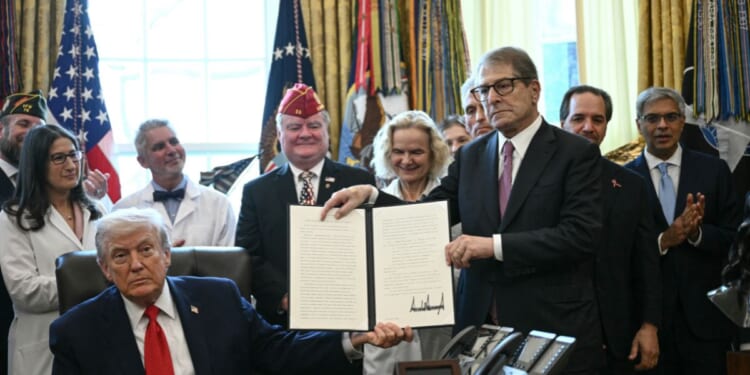 President Donald Trump and Howard Kessler, founder of the Commonwealth Project, hold up an executive order easing restrictions on marijuana in the Oval Office at the White House in Washington, D.C., on Dec. 18, 2025.