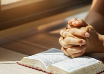 Hands on the Bible in a prayerful position.