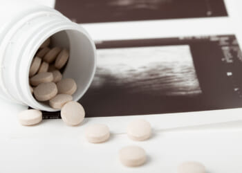Pills spill out of a white bottle onto the edge of an ultrasound.