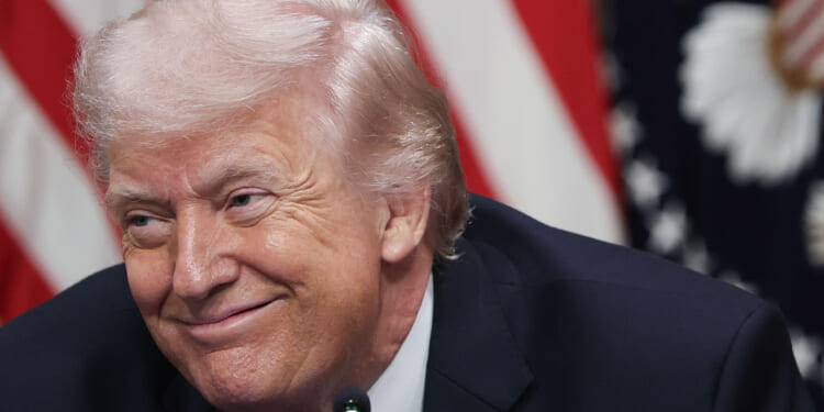 Close-up of Donald Trump grinning, with an American flag as a backdrop.