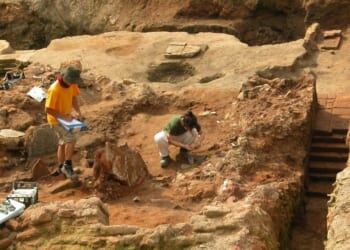 A stock photograph of two archeologists at work at a dig site.
