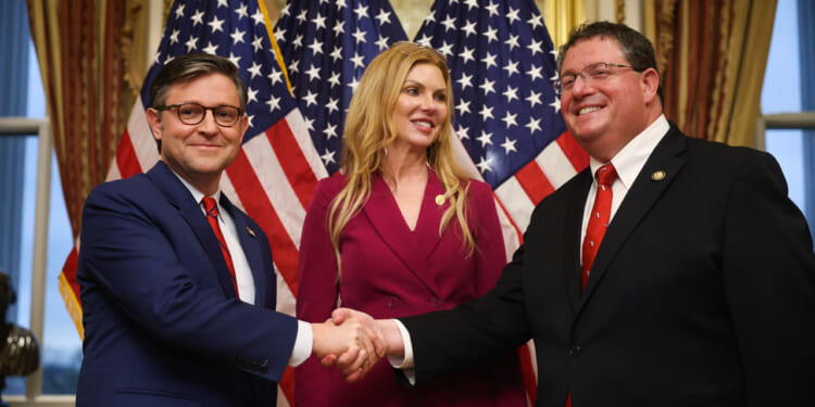 Rep. Mike Johnson (R-LA) (L) participates in a ceremonial swearing-in with Rep. Randy Fine (R-FL) (R) with wife Wendy Fine (C).
